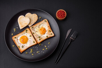 Heart shaped fried egg in bread toast with sesame seeds, flax seeds and pumpkin seeds on a black plate