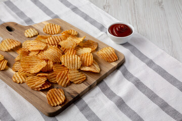 Barbeque Potato Chips on a wooden board, low angle view. Copy space.