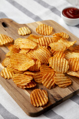 Barbeque Potato Chips on a wooden board, side view.