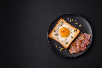 Heart shaped fried egg in bread toast with sesame seeds, flax seeds and pumpkin seeds on a black plate