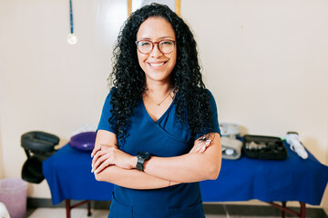 Crossed arms african american physical therapist woman. Smiling woman chiropractor in uniform with arms crossed, Portrait of smiling woman physiotherapist - obrazy, fototapety, plakaty