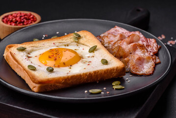 Heart shaped fried egg in bread toast with sesame seeds, flax seeds and pumpkin seeds on a black plate