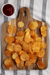 Barbeque Potato Chips on a wooden board, top view. Flat lay, overhead, from above.