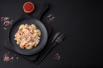 Delicious pasta with bacon and parmesan cheese on a black ceramic plate