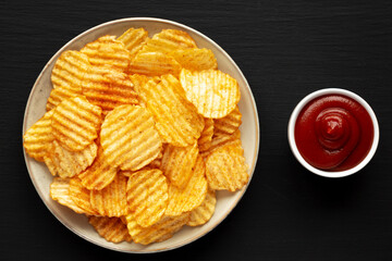 Barbeque Potato Chips on a plate on a black background, top view. Flat lay, overhead, from above.