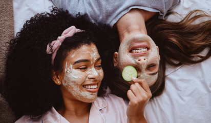 Facial, cucumber or beauty with girl best friends lying on the floor together for treatment at a sleepover. Face mask, skincare or natural care with a female and friend at home to relax while bonding