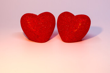 Fototapeta premium Two red hearts on a pink background