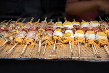 Street food , Japanese Pizza or Okonomiyaki roll on top egg ,cheese and bacan with chopsticks  ready to eat.
