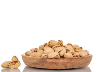 Many peeled pistachios in a wooden bowl, close-up, isolated on white.