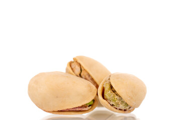 Three unpeeled pistachios, close-up, isolated on white.