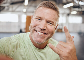 Selfie, fitness and portrait of man in gym with rock hand sign for muscle, wellness and cardio workout. Smile, healthy body and face of senior male for bodybuilder training, exercise and sports goals