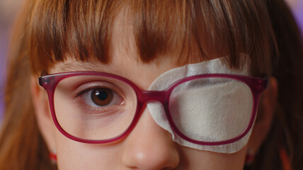Close-up portrait of sick ill girl face looking at camera, having protective bandage plaster patch...
