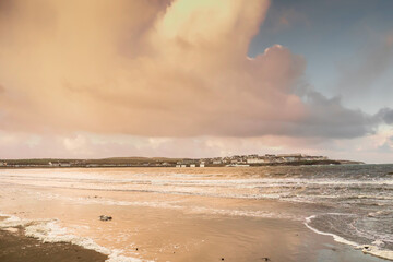 View on Kilkee beach and town houses in the background. County Clare, Ireland. Nobody. Popular summer resort. Atlantic ocean, Irish seascape. Cloudy sunset sky.