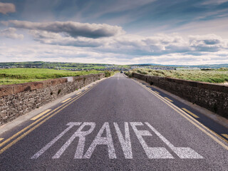 Small narrow high quality asphalt road with stone fences on each side and big sign travel. Blue cloudy sky and green fields. Warm sunny day. West of Ireland. Tourism concept.