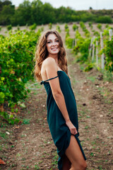 a woman from the village in a green dress stands in a vineyard