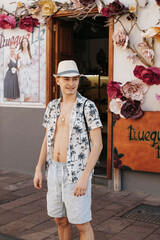 Portret młodego chłopaka w słomianym kapeluszu oraz rozpiętej koszuli w wakacyjny wzór, La Gomera