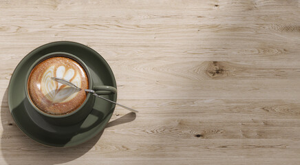 Top view of beautiful heart shape latte art in sage green coffee cup, saucer on wooden table with...