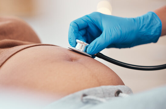 Hand, Stethoscope And The Belly Of A Woman Pregnant In A Hospital For Prenatal Exam Or Checkup In The Hospital. Healthcare, Medical And Pregancy With A Doctor Listening To The Baby Of A Mother To Be