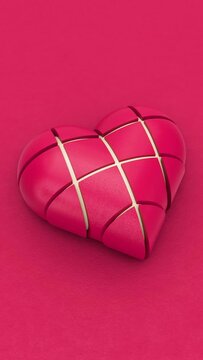 Vertical animation of beating heart composed by geometric pieces over viva magenta colour background with copy space. The pieces open and close and reveal cream colour indoor. Endless loop 3D render.
