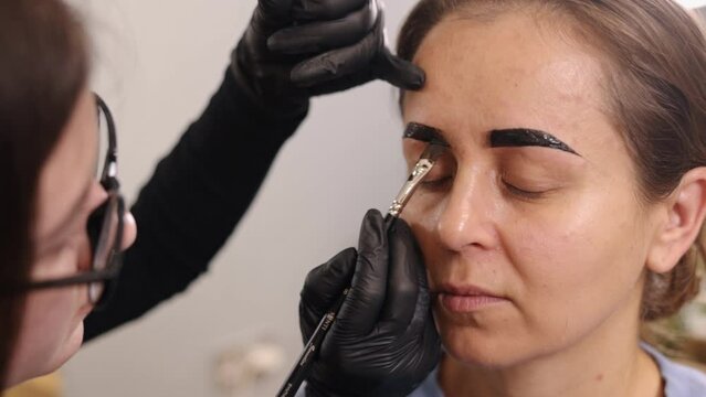 beauty salon, eyebrow correction, beauty product. Young woman undergoing an eyebrow correction procedure in beauty salon, microblading is concept for eyebrows, painting eyebrows in different colors