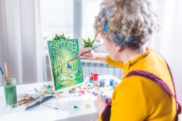 Beautiful girl artist paints on canvas at home