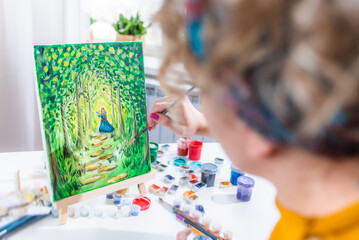 Beautiful girl artist paints on canvas at home