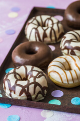 Chocolate Donuts, Berliner, Krapfen on a rusty tray on pink background