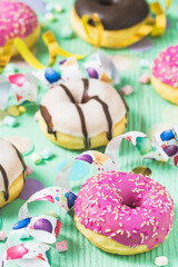 Donuts, Berliner, Krapfen with streamers and confetti. Colorful picture of carnival, birthday and fasching, green background, vertical