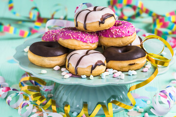 Donuts, Berliner, Krapfen with streamers and confetti. Colorful picture of carnival, birthday and fasching, green background