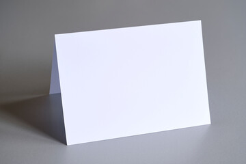 Standing blank empty rectangular greeting card mock up on grey background. For use as a Christmas, birthday, wedding or celebration background template.	