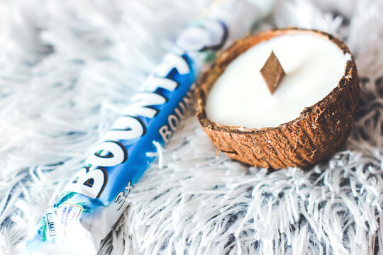 Chernihiv, Ukraine - July 24, 2022: Bounty chocolate bar and coconut. Coconut candle.