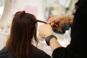 Obraz na płótnie Canvas 女性の髪を結ぶ男性美容師