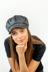 Gorgeous dark brown girl in a trendy leather hat looks into the camera with her face resting on the back of her hand