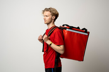Side look on delivery man in red uniform with thermal backpack for food. Takeaway food delivery....