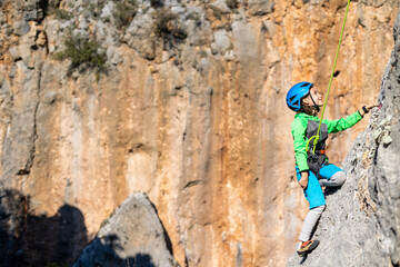 Child rock climber. The boy climbs the rock. The child is engaged in rock climbing on natural...