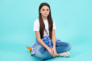 Obraz premium Trendy beautiful teenage model posing on blue studio background. Child girl in t-shirt and jeans. Studio shot. Teen fashion.
