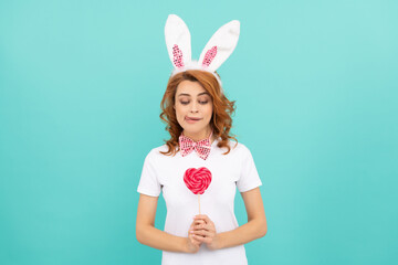 curious easter woman wear bunny ears hold heart lollipop