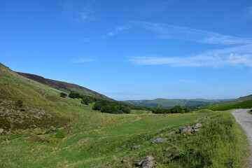 Naklejka premium View from the top of a mountain with green fields and a blue sky background. Taken in Oldham England. 