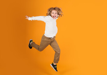 Fototapeta na wymiar Full length of excited kid jumping. Little child jumping over a yellow background.