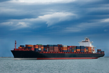 Nave mercantile porta container, ormeggiata al largo di un porto del Mediterraneo, il cielo è minaccioso