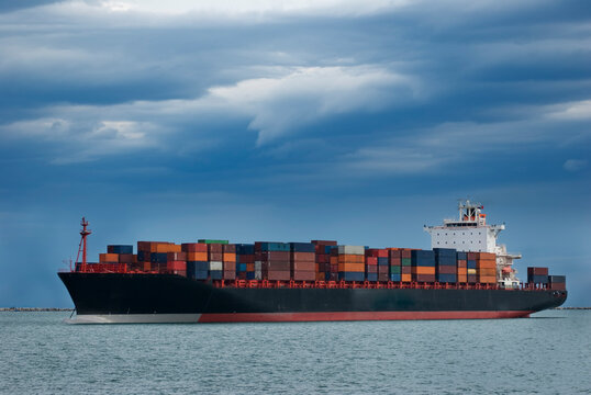Nave mercantile porta container, ormeggiata al largo di un porto del Mediterraneo, il cielo è minaccioso