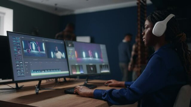 female film editor processing video clip in studio, montage and color grading, post-production