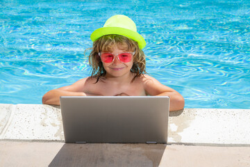 Child working on laptop computer at swimming pool. Summer online technology. Traveler relaxing on tropical water in summer holidays vacation. Travel trip, kid using laptop.