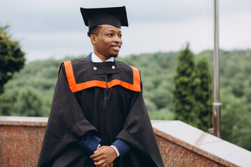 Young smiling black male on his graduation day in university. Education, qualification and gown...
