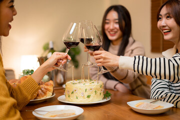 Young smiling woman drinking and clinking glass of wine to toasting with happiness while celebrating in new year party at home