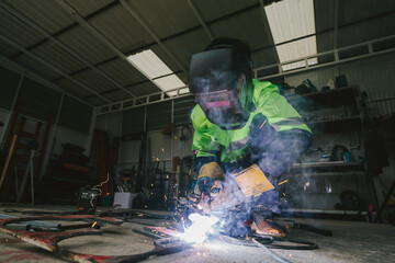 Asian welder wearing protective safety helmet welding with electric welding machine in workshop with skill