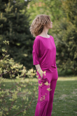 Fototapeta premium Outdoor portrait of female model in bright pink outfit enjoying in nature during beautiful summer day