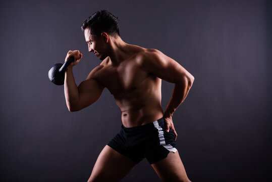Sporty man working out with a kettlebell. Photo of man on dark background. Strength and motivation