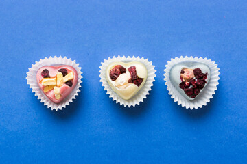 chocolate sweets in the form of a heart with fruits and nuts on a colored background. top view with space for text, holiday concept