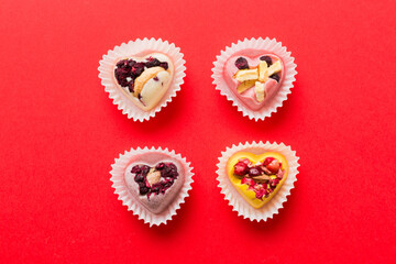 chocolate sweets in the form of a heart with fruits and nuts on a colored background. top view with space for text, holiday concept